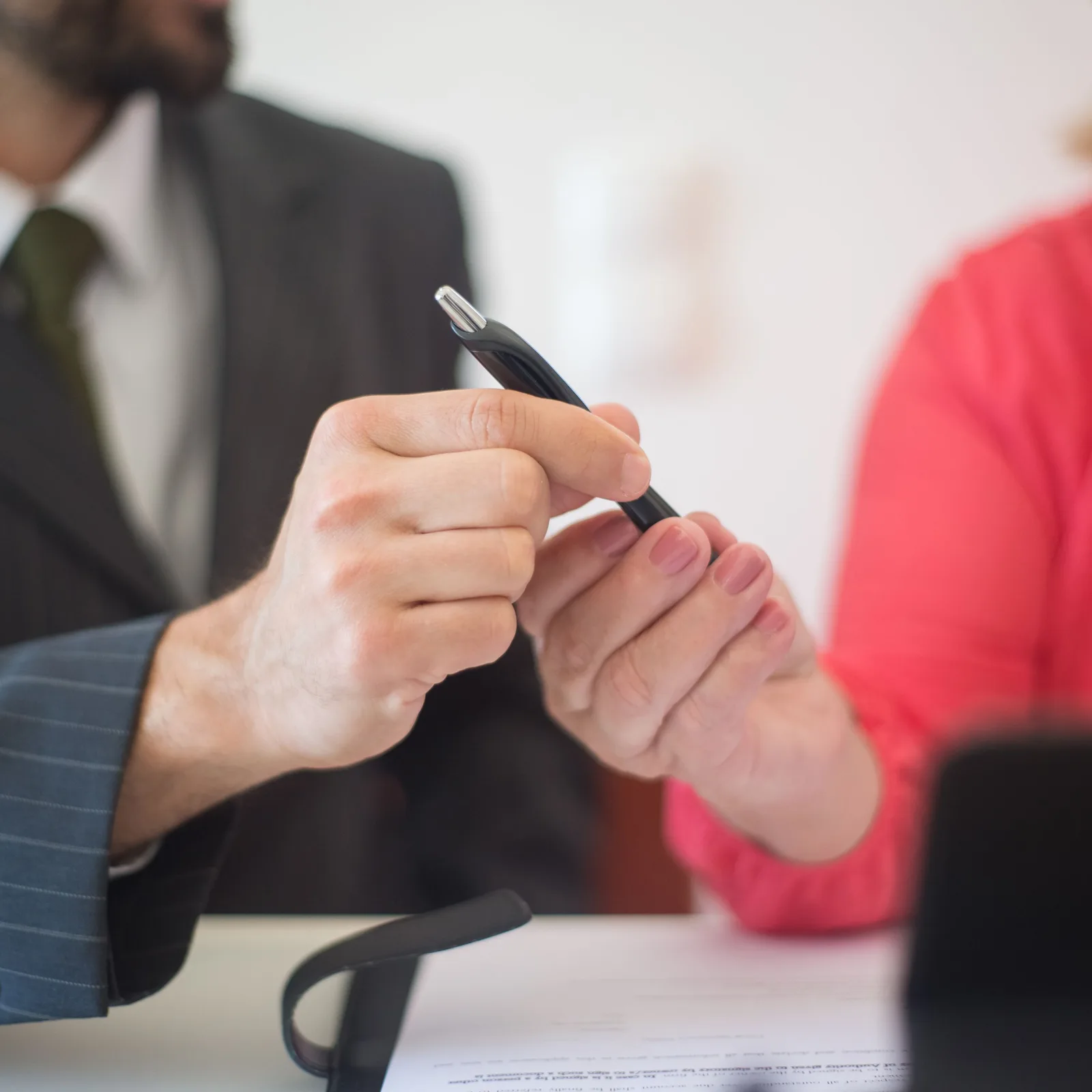 Deux mains relisent une offre sur une planchette, l’une tient un stylo, l’autre pointe une ligne du document